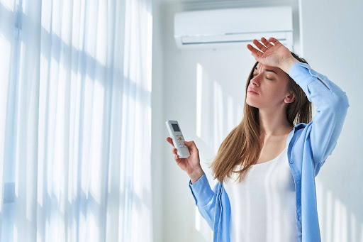 a lady feeling hot under an air conditioner